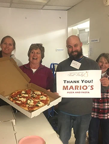 GCFP volunteers and Staff holding a large Mario's Pizza and a sign that says, "Thank You! Marios!"