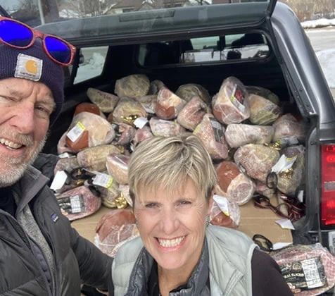 A man and woman volunteer to deliver hams to those in need.