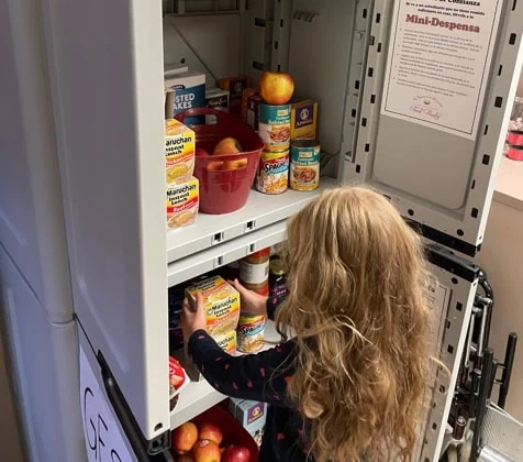 An elementary student picks out an item from a school pantry.