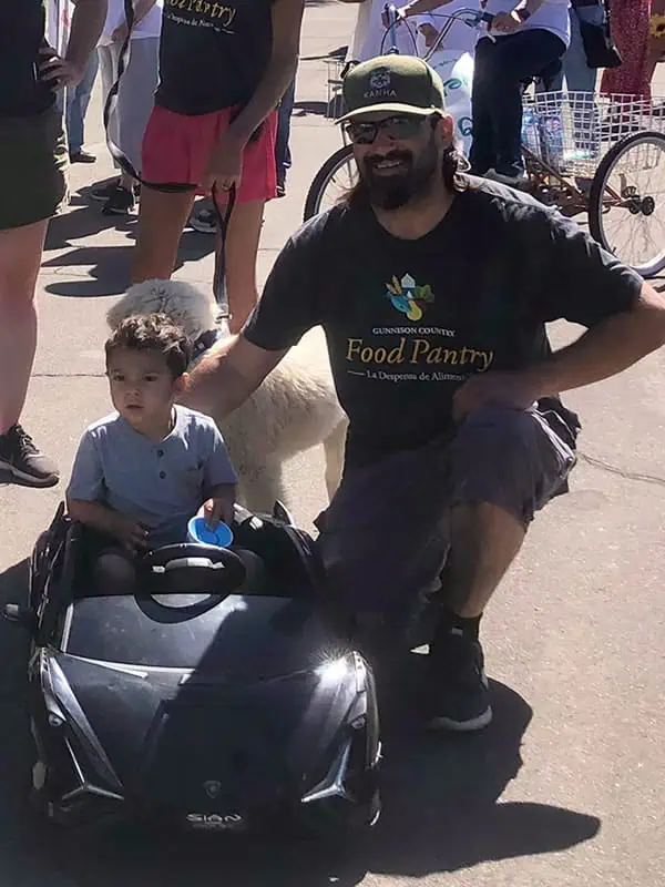 Un hombre y su hijo en un auto del tamaño de un niño sonríen ante el desfile.