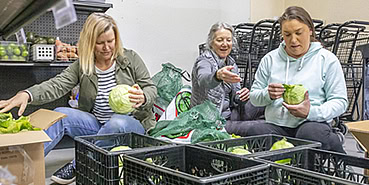 Three volunteers help sort vegetables at the Food Pantry.