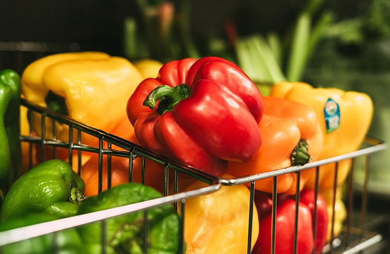 Beautiful red, green, and yellow sweet peppers in wire baskets.