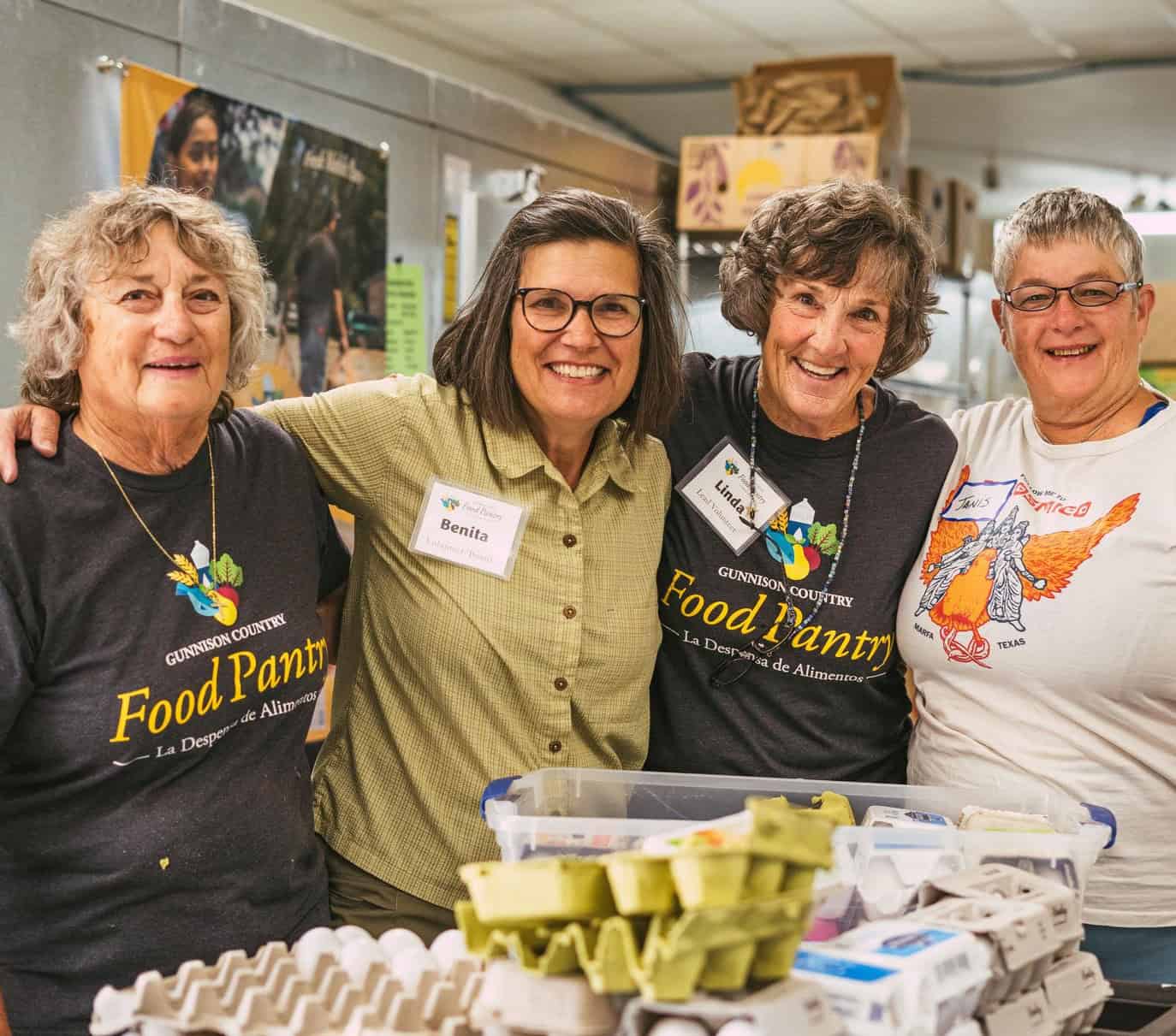 Four volunteers smile standing in front of a table full of egg cartons.