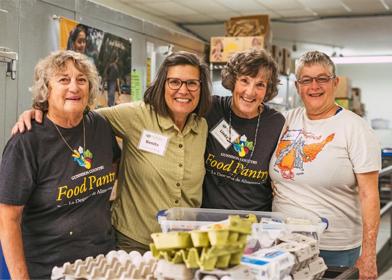 Four volunteers smile standing in front of a table full of egg cartons.