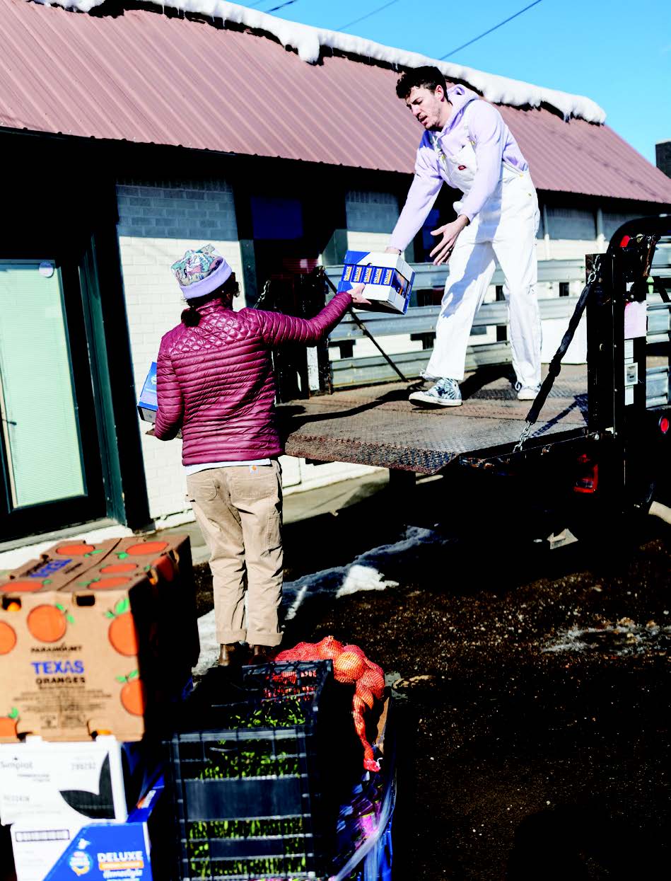 Two volunteers are unloading a large-truck full of food.